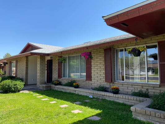 Front view of Sunny Days Senior Living with a garden and flower pots.