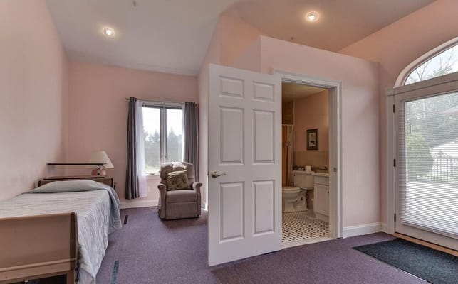 Bright bedroom with a bed, armchair, and adjoining bathroom