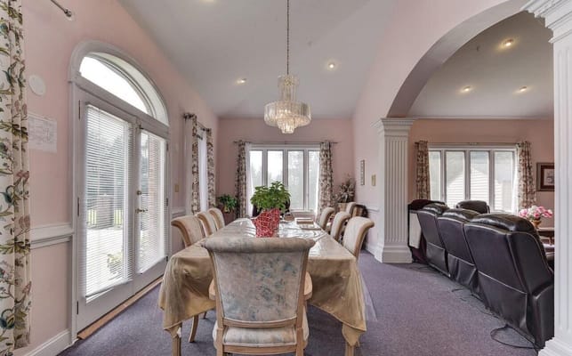 A spacious dining room with a large table and comfortable seating in a senior living facility.