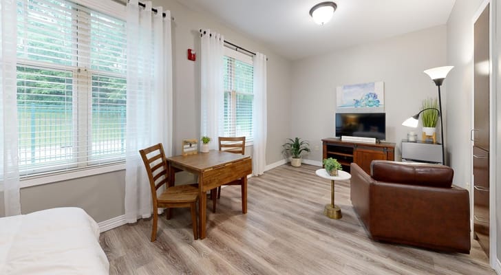 A cozy living room featuring a dining table, chairs, and a television.