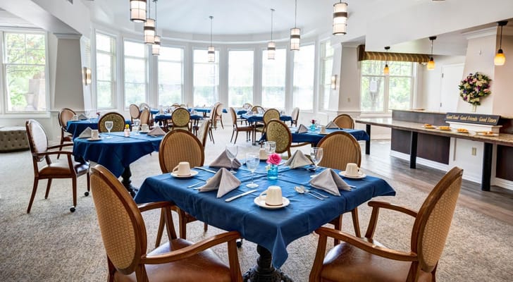 Elegant dining room with blue tablecloths and floral decorations.