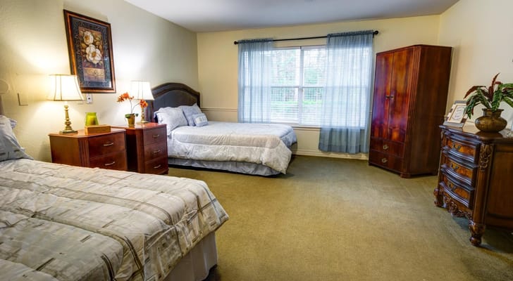 A spacious bedroom with two beds, nightstands, and a wardrobe.