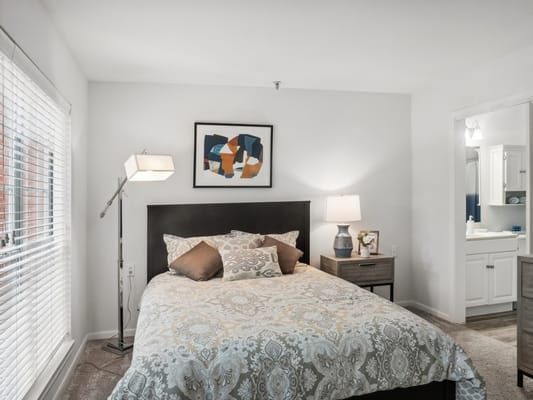 A well-decorated bedroom with a bed, lamp, and nightstand at The Forum at The Woodlands.