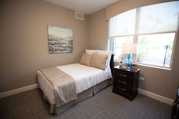 A cozy bedroom featuring a bed with decorative pillows and a bedside table.
