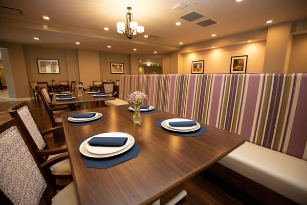 Dining table set up with blue napkins and floral centerpiece in a senior living facility