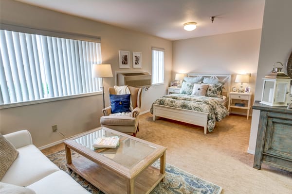 A well-decorated bedroom with a bed, armchair, and side tables