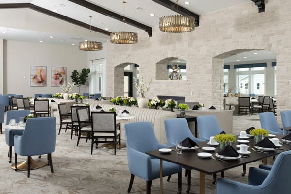 Dining room with blue chairs and floral centerpieces in senior living facility