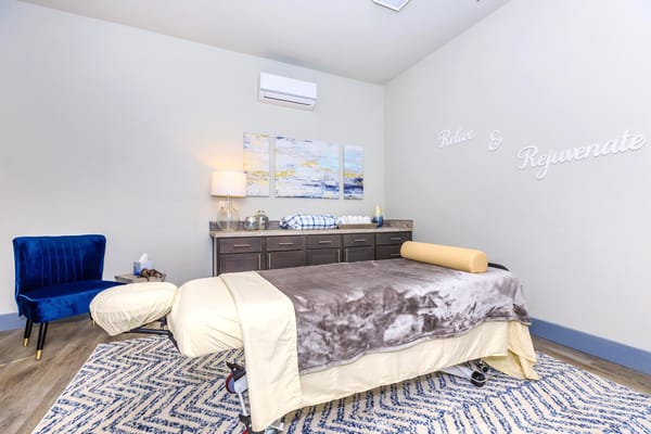 Cozy relaxation room with a massage table and blue chair