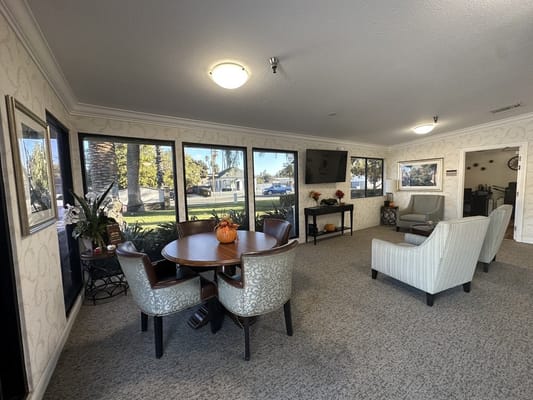 Cozy common area with a round table and chairs, large windows, and comfortable seating.