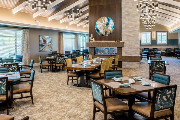 A bright dining area with wooden tables and patterned chairs at Verena at Hilliard.