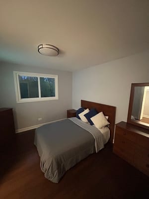 A cozy bedroom with a bed, blue and white pillows, and a window.