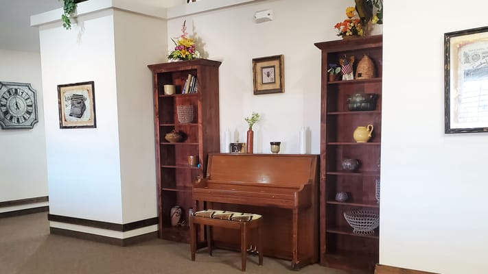 Interior view of a common area with a piano and shelves