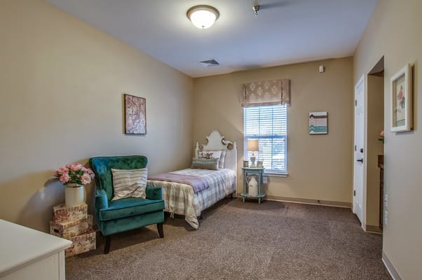 Cozy resident room with a bed and green chair