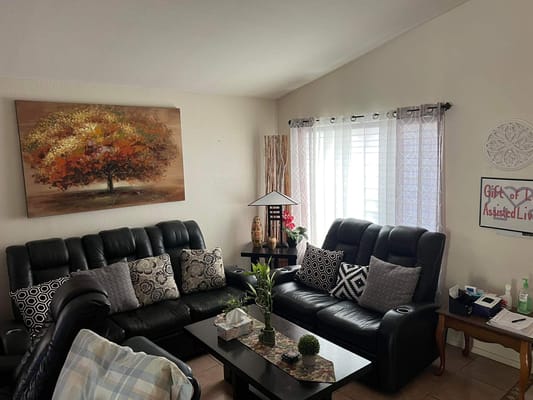 Seating area in a cozy living room with dark leather sofas and decorative pillows.