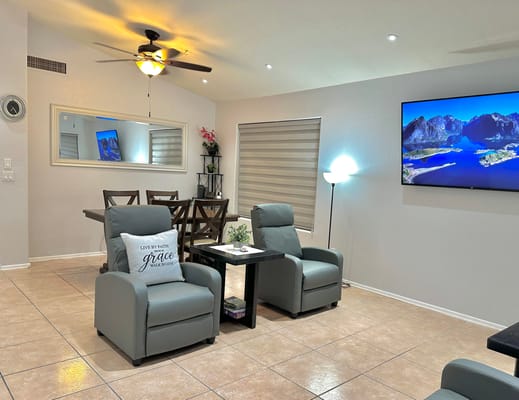 Common living area with chairs, dining table, and wall-mounted TV