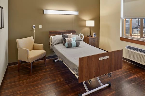 A private resident room with a bed and chair