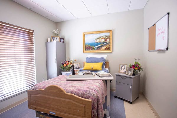 A cozy resident room with a bed, flowers, and a painting