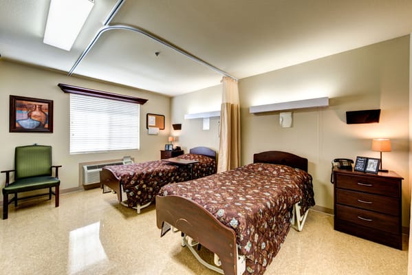 Two twin beds with floral bedding in a well-lit bedroom.