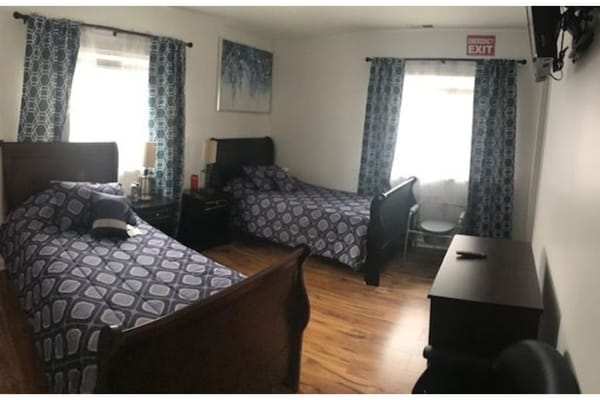 A cozy bedroom with two beds and window curtains in a senior living facility.