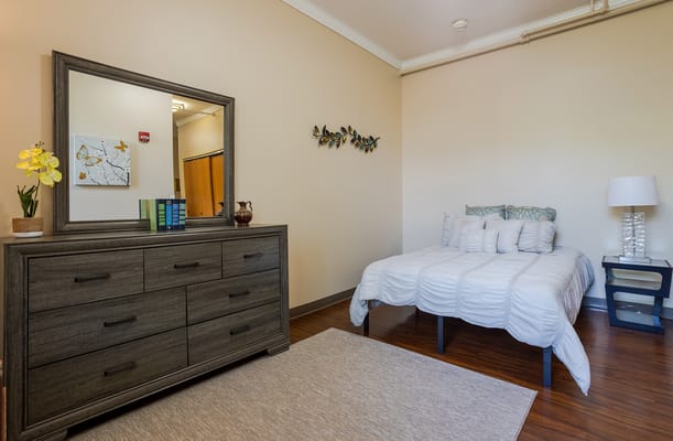 Brightly decorated private resident room with a bed and dresser