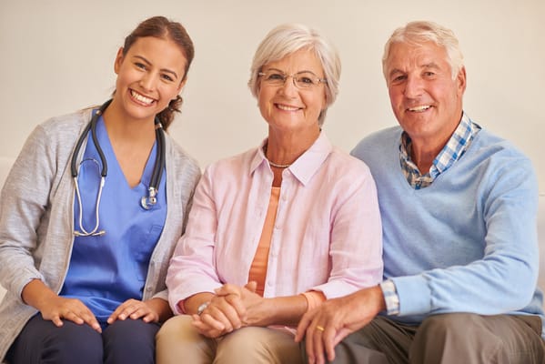 A nurse with two smiling residents in a care home