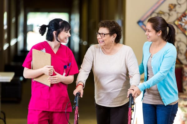 Care staff assisting a resident in a hallway.