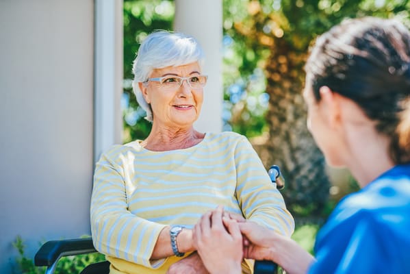 Senior resident smiling with caregiver in an outdoor setting