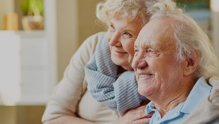 Elderly couple smiling together in a cozy interior