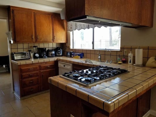 A kitchen area with wooden cabinets and tile countertops