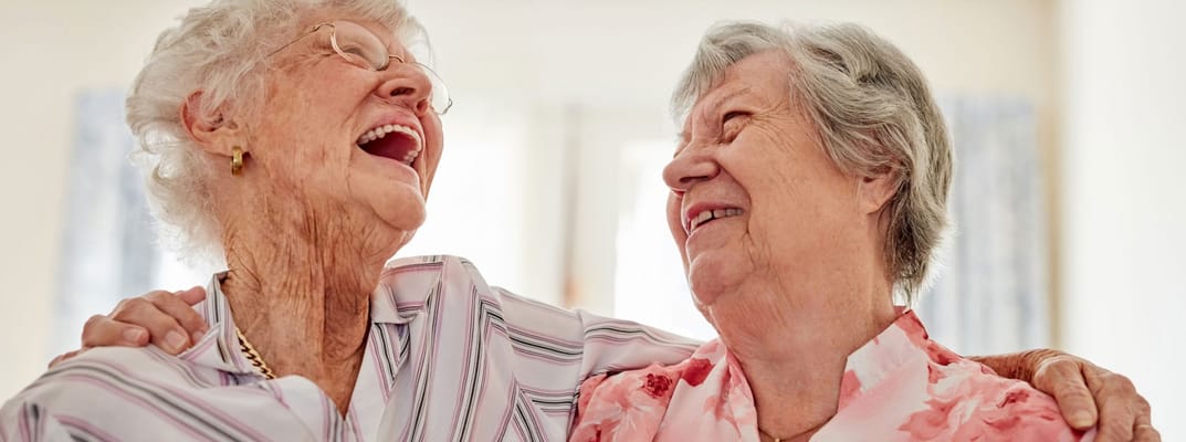 Two elderly women enjoying a candid moment together
