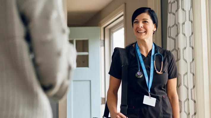 A nurse smiling while greeting a resident