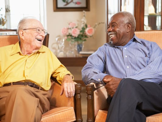 Two seniors laughing together in a cozy lounge