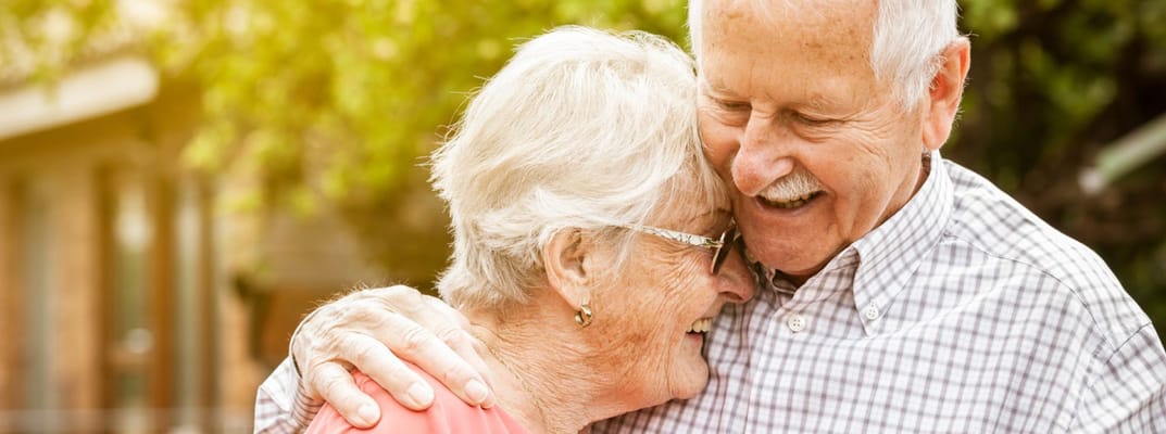 Senior couple embracing outdoors, smiling happily