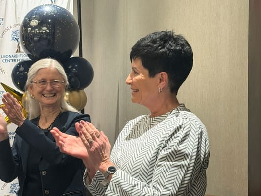 Two women smiling and clapping at a celebration event