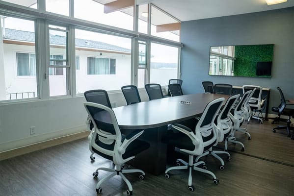 A bright interior meeting room with large windows and chairs
