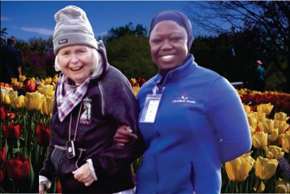 Resident and staff member smiling in a flower garden