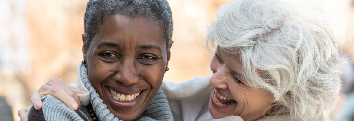 Two smiling women embracing outdoors