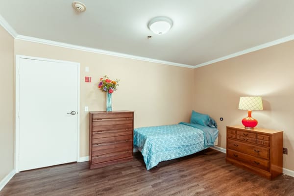 Private room with a bed, dresser, and lamp