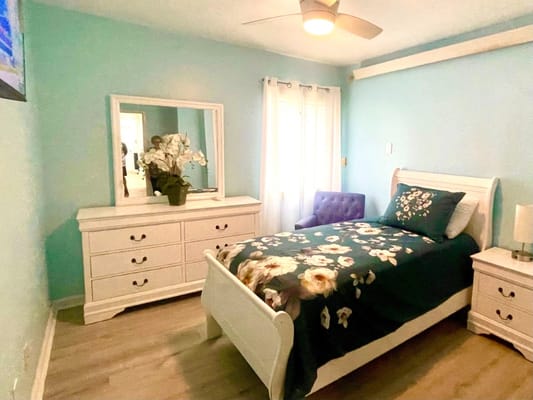 A well-furnished private resident room with a bed and dresser