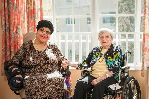 Two residents sitting together and holding hands
