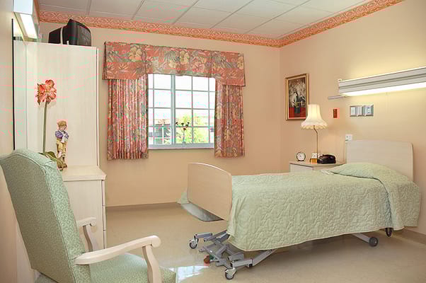 A well-furnished resident room with a bed and chair