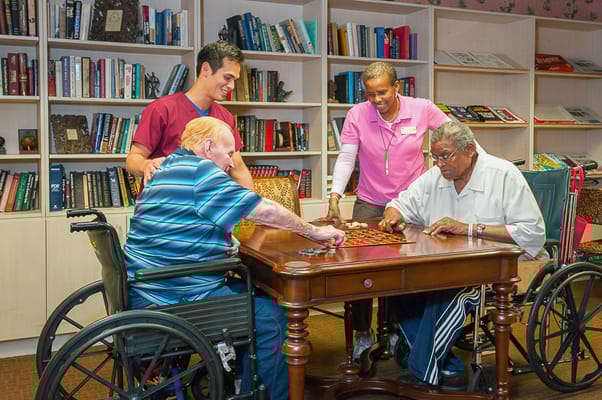 Residents engaging in a board game with staff assistance