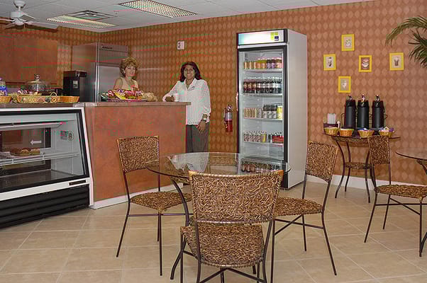 Two staff members in a common area with seating and refreshments