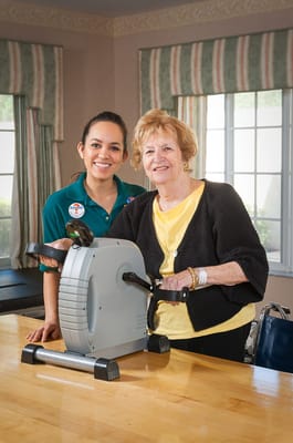 A caregiver assisting a resident with exercise equipment