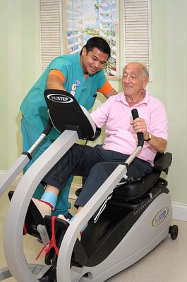Staff assisting a resident using exercise equipment