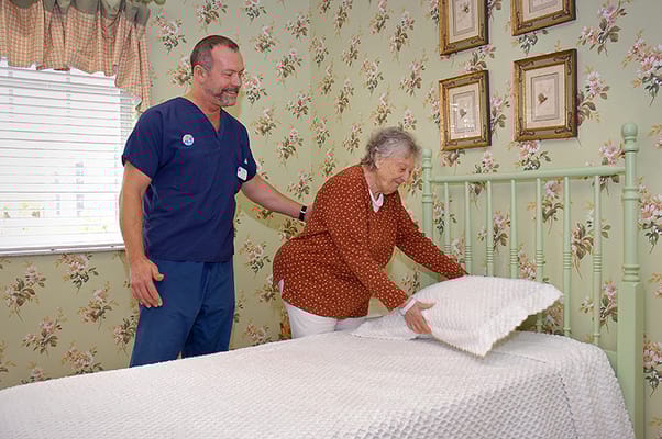 Staff assisting a resident in a warmly decorated room