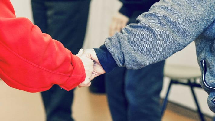 Close-up of two hands shaking in a communal space