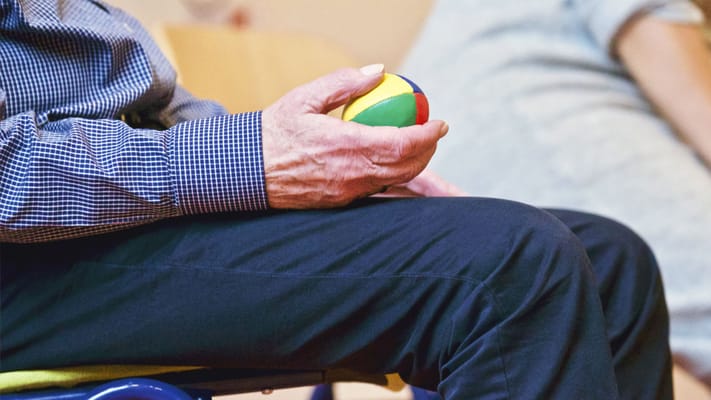 A senior holding a multi-colored stress ball during an activity