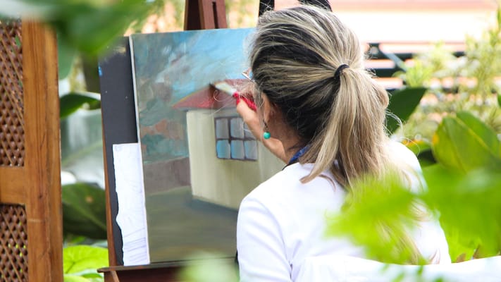 A woman painting outdoors in a garden setting