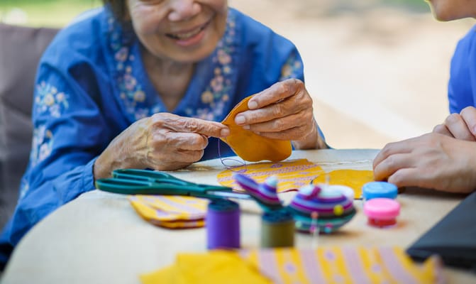 An elderly woman sewing colorful fabric pieces